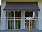 Un store rayé au-dessus d'un balcon avec une balustrade blanche
