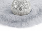 Un tapis gris en fourrure avec une boule en verre.