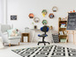 Une chambre d'enfant avec un fauteuil gris, un bureau avec une chaise et un tapis noir et blanc.