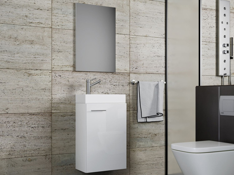 Une salle de bain blanche avec un lavabo, un miroir et des toilettes.