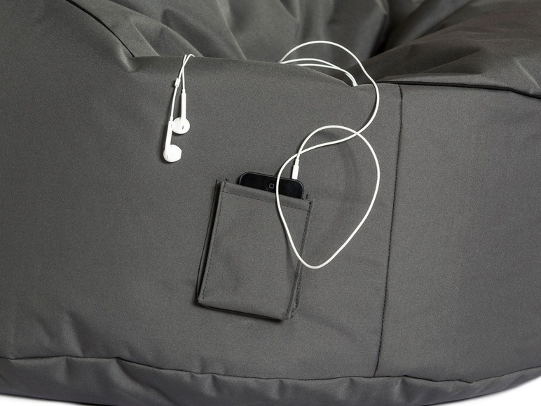 Un pouf gris avec une poche, un téléphone et des écouteurs.
