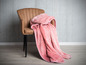 Une couverture en polaire rose sur un fauteuil marron