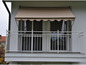 Un balcon avec une marquise beige et une balustrade blanche.