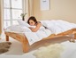Une femme est allongée dans un lit avec une couette et un oreiller de la marque Nabrü.