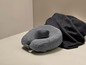 Un coussin de voyage Synca gris et une écharpe en laine foncée.