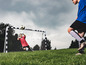 Un garçon attrape un ballon de football devant un but Hudora.