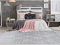 Un tapis gris avec un motif blanc dans une chambre à coucher avec un lit.