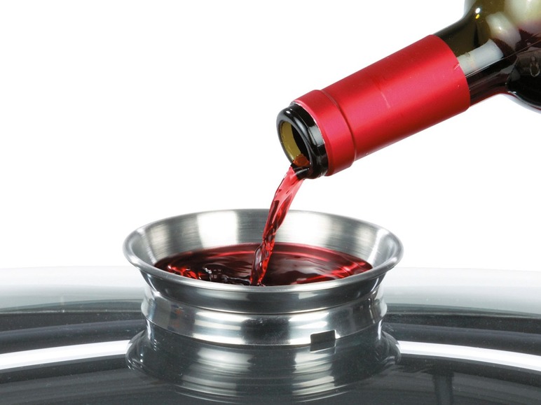 Du vin est versé dans un récipient métallique.