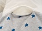 Un pantalon gris à imprimé étoiles et une poche en maille blanche avec fermeture éclair.