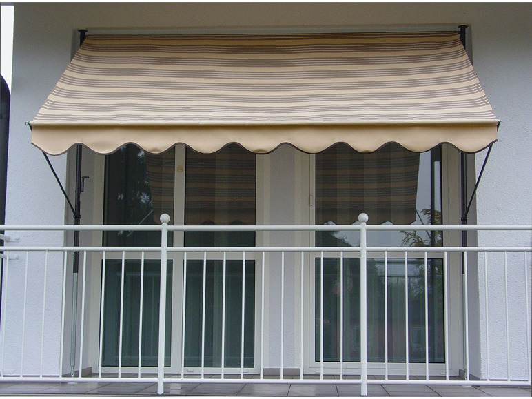 Un store rayé au-dessus d'un balcon avec une balustrade blanche.