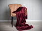 Une couverture en polaire rouge sur un fauteuil marron.