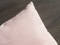Un coussin rose sur un sol en bois.