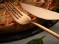 Une fourchette et un couteau rose gold d'Echtwerk, à côté d'une pizza.
