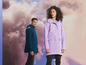 Deux personnes portant des imperméables, une femme avec un manteau lilas et un homme avec un manteau bleu foncé.