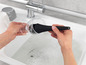 Une personne lave un verre avec une brosse dans l'évier.