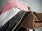 Plusieurs couvertures douces en rose, blanc, gris et marron sur une chaise.