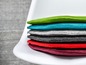Pile de coussins de siège en feutre de couleur sur une chaise blanche.