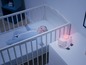 Un bébé dort dans un berceau avec un projecteur en forme de mouton.