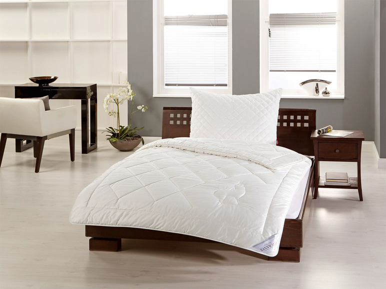 Une couette et un oreiller blancs sur un lit avec un cadre en bois foncé