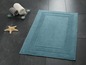 Un tapis de bain bleu avec une bordure décorative.