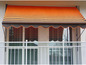 Un store banne orange et brun à rayures au-dessus d'un balcon.
