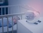 Une veilleuse en forme de mouton à côté d'un bébé dans un berceau.