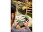 Une personne construit des bonsaïs LEGO sur une table en bois.