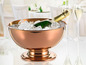 Une bouteille de champagne dans un seau à glace en cuivre avec deux verres en arrière-plan.