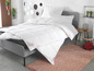 Une couette blanche de la marque Sannwald sur un lit gris.