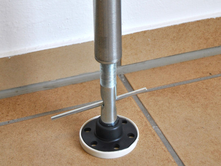 Un poteau métallique avec un filetage et un pied noir sur un sol en carrelage.