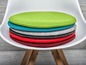 Pile de coussins ronds en feutre de couleurs différentes sur une chaise blanche