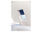 Une chambre à coucher avec une fenêtre de toit et un store solaire bleu.