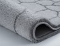 Un tapis de bain gris avec un motif géométrique.
