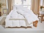 Une couette blanche et des oreillers sur un cadre de lit en bois.