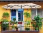 Un parasol beige au-dessus d'un balcon avec des pots de fleurs.
