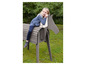 Une fille assise sur un cheval en bois dans le jardin.