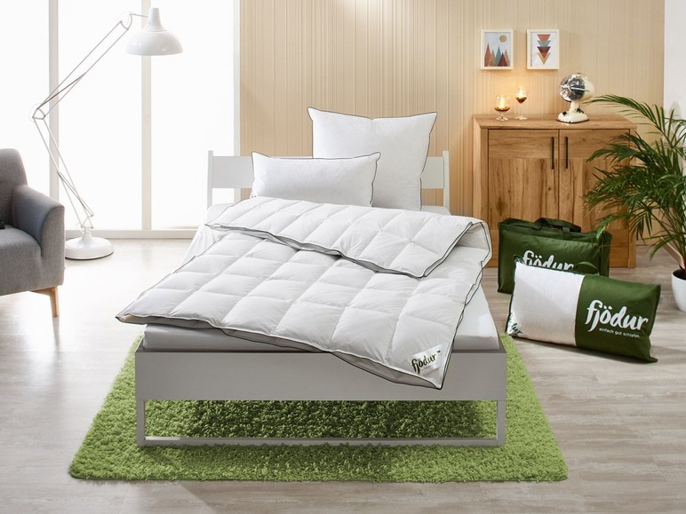 Une couette et un oreiller blancs Fjodor sur un lit avec un tapis vert.