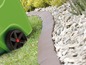 Un conteneur vert avec des roues à côté d'une bordure de jardin brune.