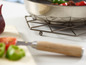 Un dessous de plat en métal pour une casserole, avec un couteau en bois.