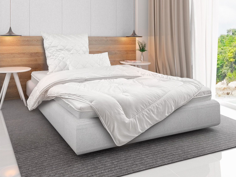 Une couette et un oreiller blancs sur un lit avec une tête de lit blanche.