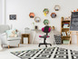 Une chambre d'enfant avec un fauteuil gris, une chaise de bureau noire et une bibliothèque.