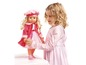 Une fille joue avec une poupée en robe rose.