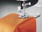 Une machine à coudre cousant du tissu orange.