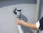 Une main connectant un tuyau à une valve de vidange d'une piscine.