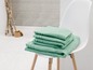Une pile de serviettes de bain couleur menthe sur une chaise blanche.