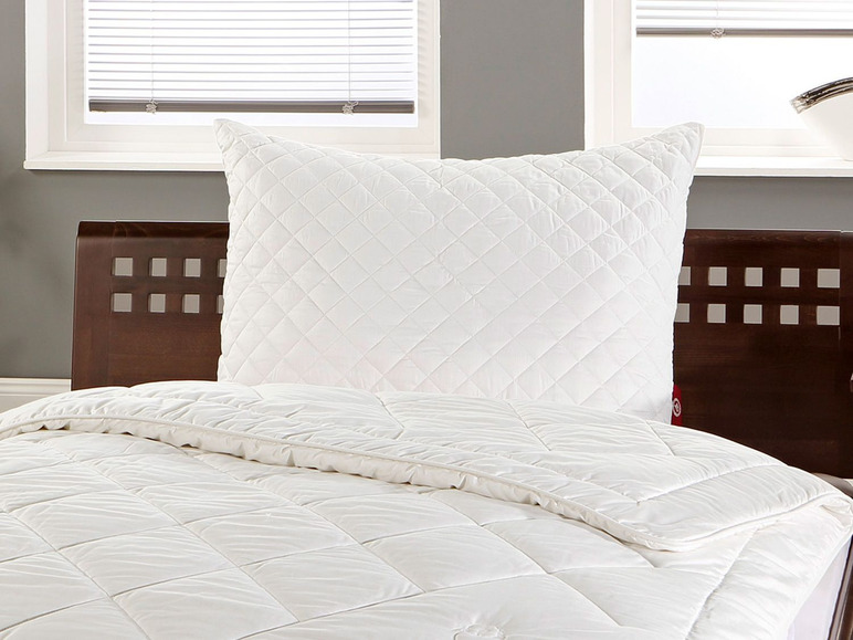 Couette et oreiller blancs sur un lit en bois.