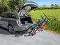 Une voiture avec un porte-vélos, sur lequel deux vélos sont chargés.