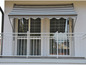 Un balcon avec un auvent rayé et une balustrade blanche.