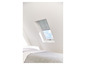 Un lit avec un velux et une store intégrée.