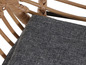 Une chaise en rotin avec un coussin gris.